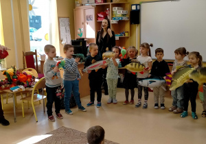 Dzieci stoją z p.Agą trzymając w rękach pluszowe ryby i śpiewając o nich piosenkę.